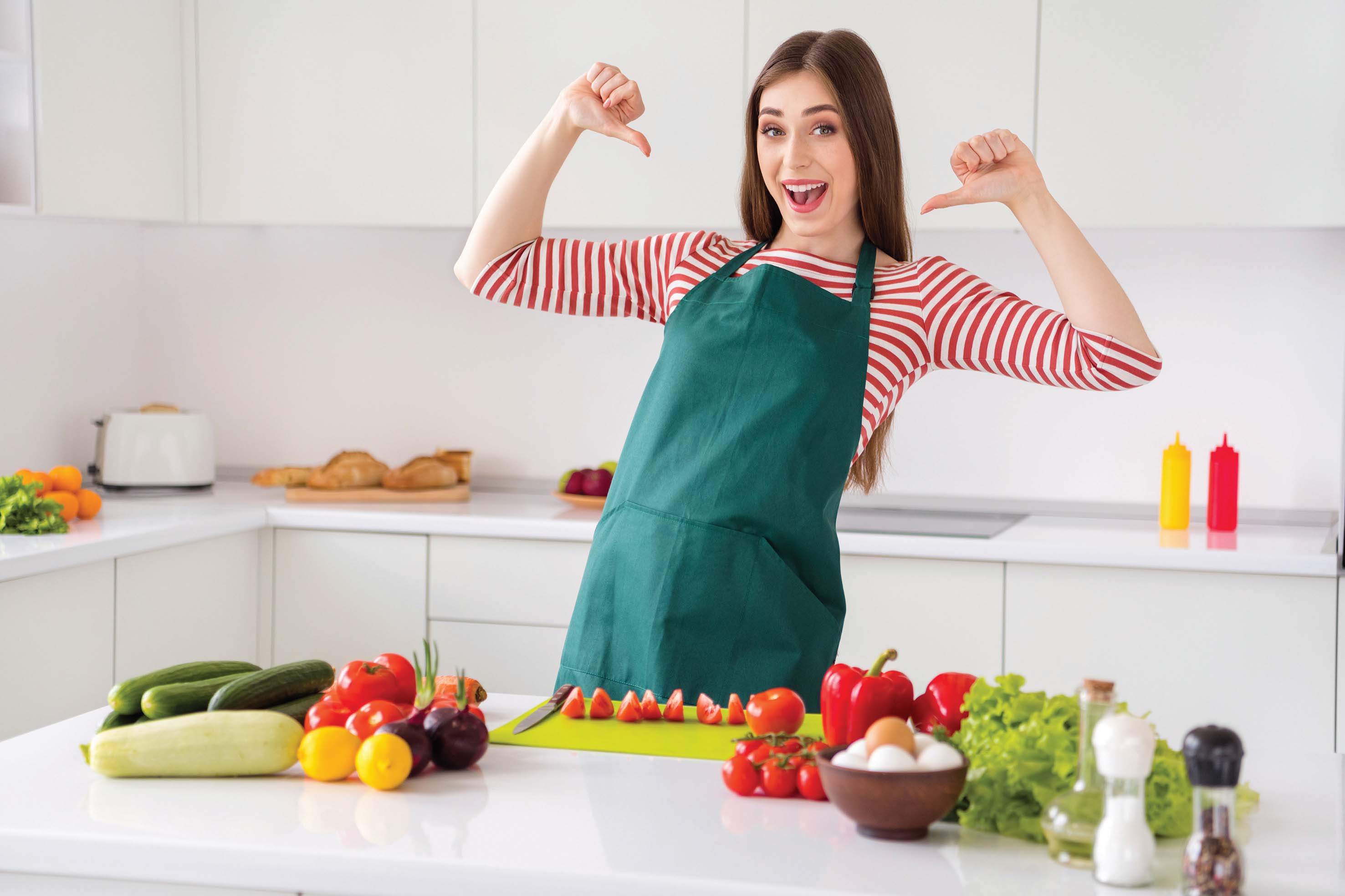 Portrait of attractive cheerful girl cooking tasty fresh dish dinner pointing at herself at home light white kitchen indoors