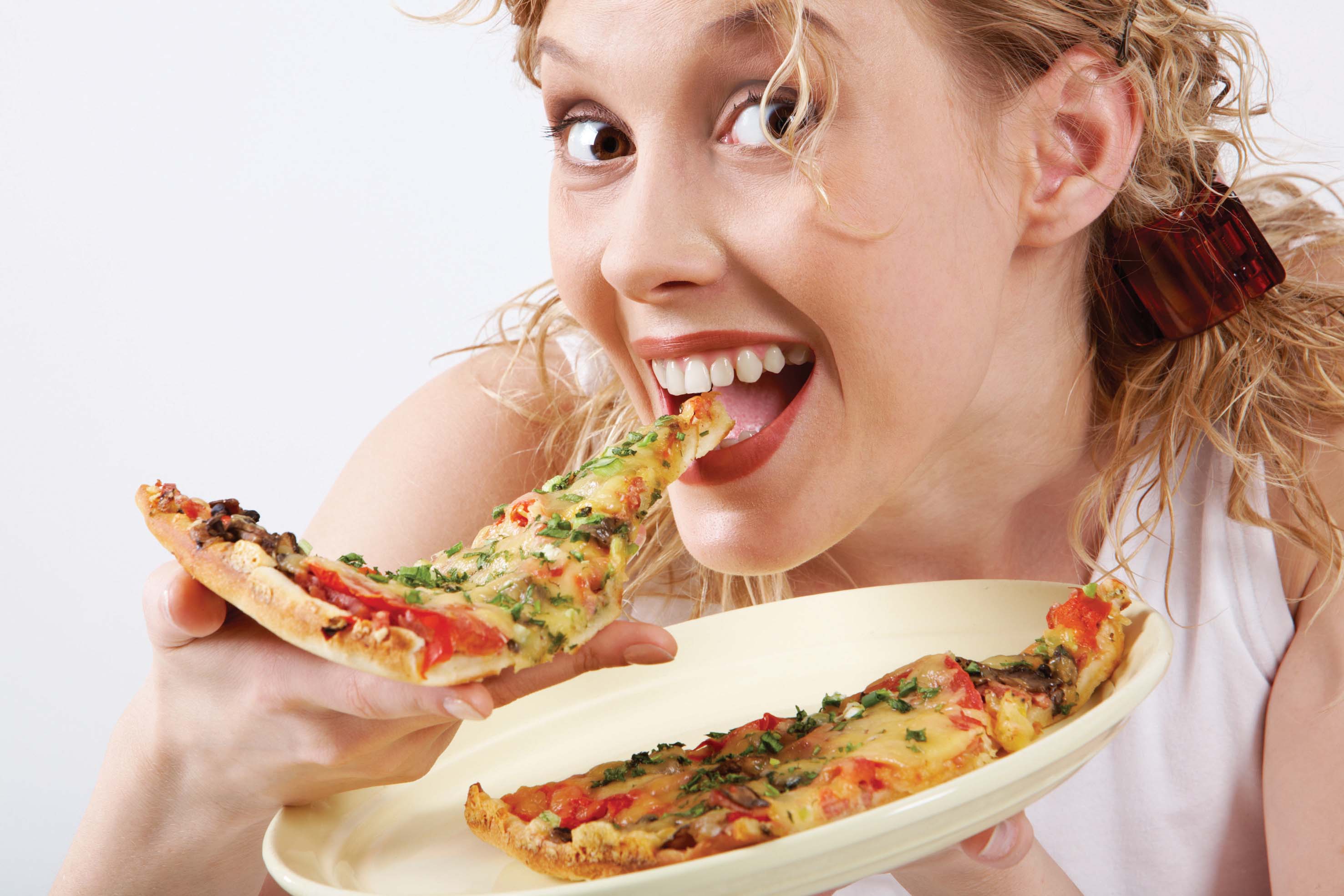 Image of happy girl eating pizza and looking at camera