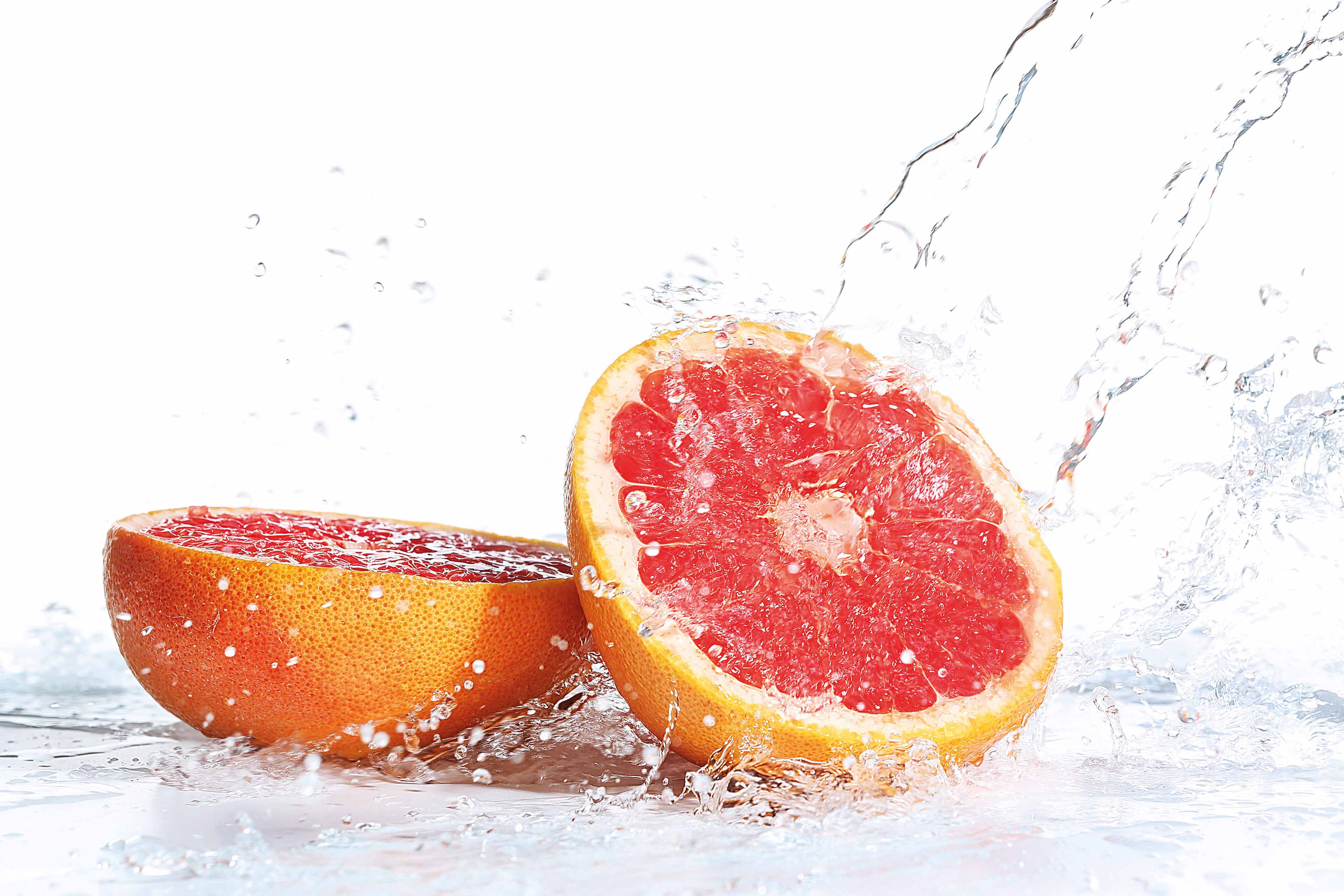 Fresh grapefruit in splashing water isolated on white